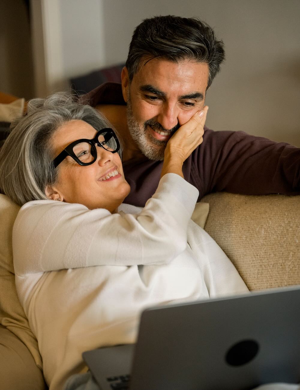 Mature couple enjoying together time with laptop at home