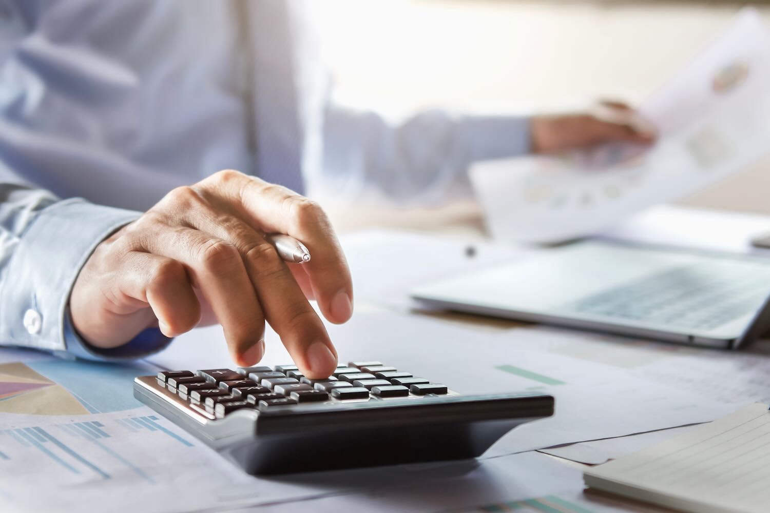 Close up of a person calculating something with a different documents in front of him
