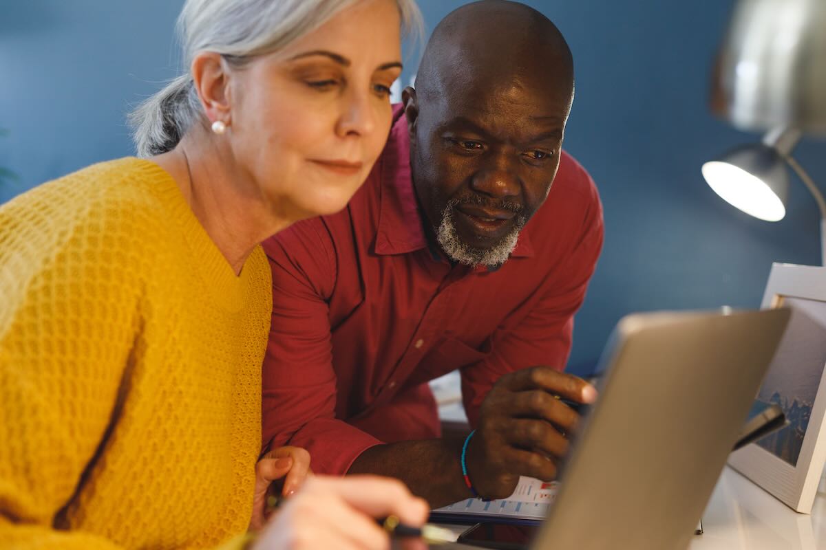 Senior diverse couple sitting at table and working